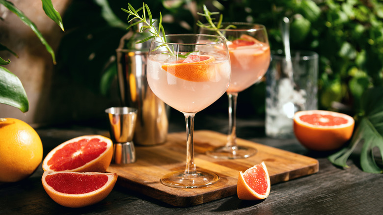 Two Palomas on a cutting board near cut grapefruit wedges