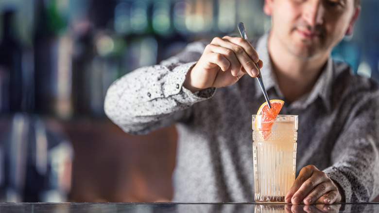 Bartender garnishing a Paloma cocktail