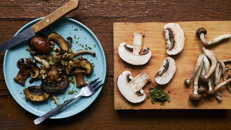 Cooked and raw mushrooms on wood background