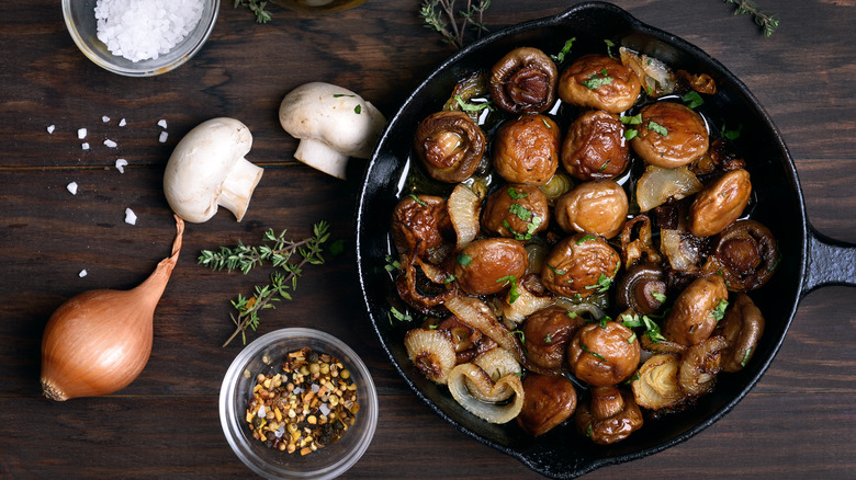 Mushrooms in a pan next to various herbs and seasonings