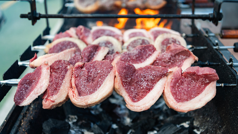 Raw picanha on a skewer above a charcoal grill