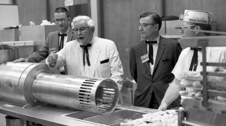 Colonel Sanders speaking with chefs in a KFC kitchen