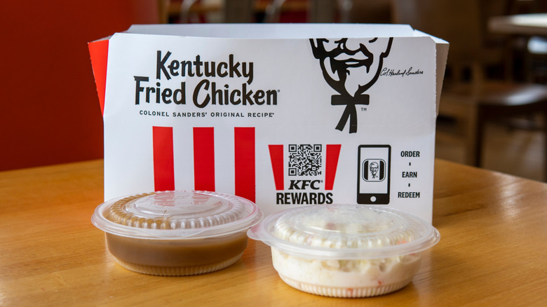 Box of KFC behind containers with mashed potatoes and gravy