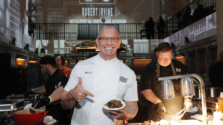 Robert Irvine poses with a plate of food at a festival