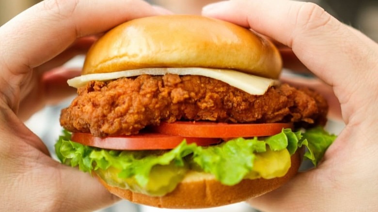 Hands hold a Chick-fil-A Spicy Deluxe Sandwich.