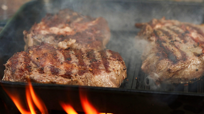 Steak on a grill with flames.