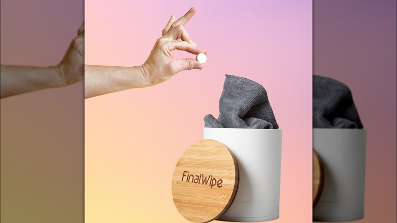 Person holding a tablet over a container with a cloth