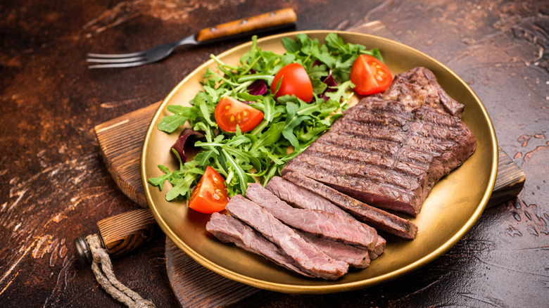 plated top sirloin steak next to a salad