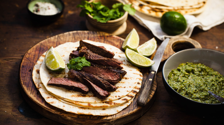 Skirt steak fajita with lime and guacamole on brown table
