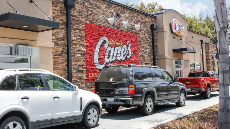 A line of cars wait at a Raising Cane's drive-thru