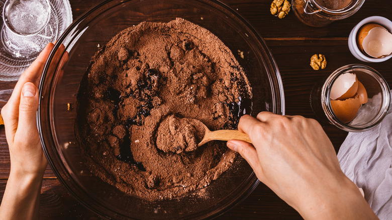 Hand mixing brownie batter with cracked egg shells on the side