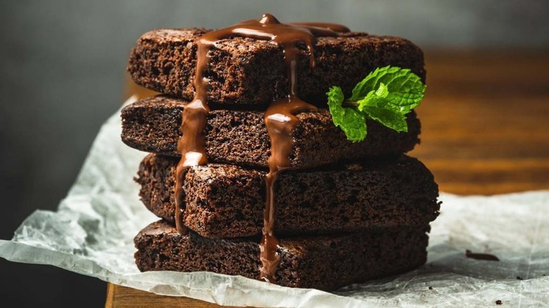 Stack of cake-like brownies with chocolate sauce melting down the top
