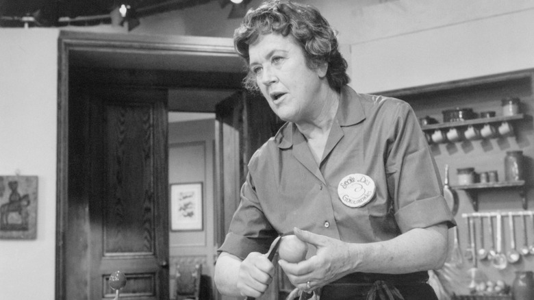 A black-and-white photo of Julia Child peeling a vegetable on the air
