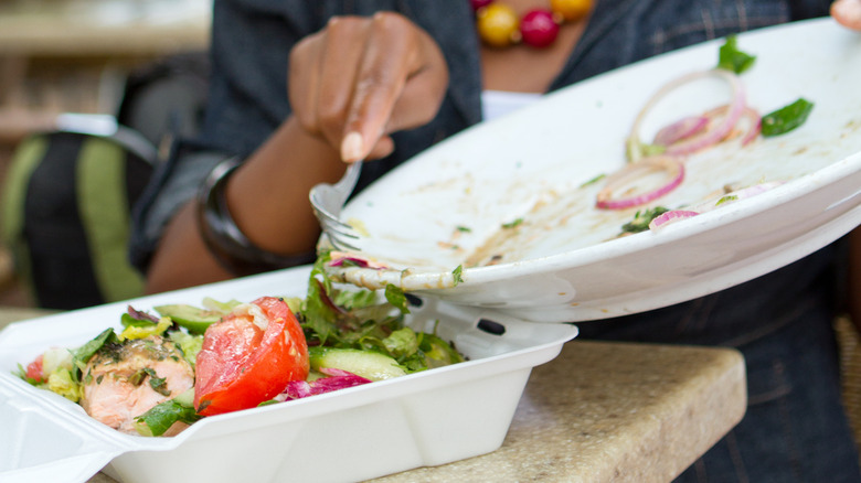 woman putting salad into takeaway carton