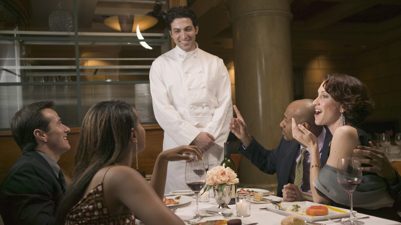 chef standing beside restaurant patrons