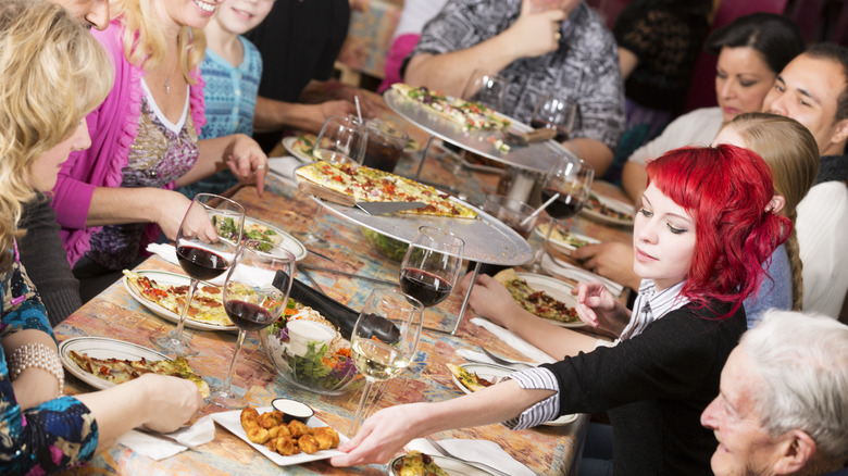 woman passing plate of food at dinner