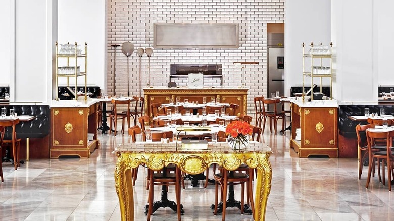 interior of a large restaurant with a gold table in the foreground and white brick wall behind