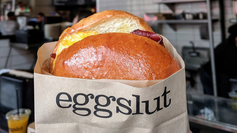 bacon and egg inside brioche bun wrapped in paper