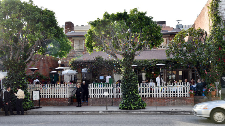 exterior of The Ivy restaurant in los angeles with a white picket fence and people dining outside