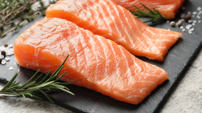 Raw salmon sits on a stone cutting board.