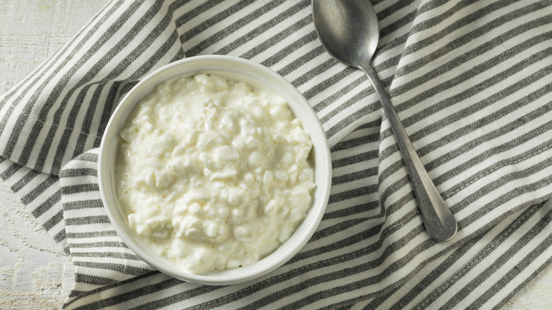 Cottage cheese sits in a bowl on top of a striped towel.
