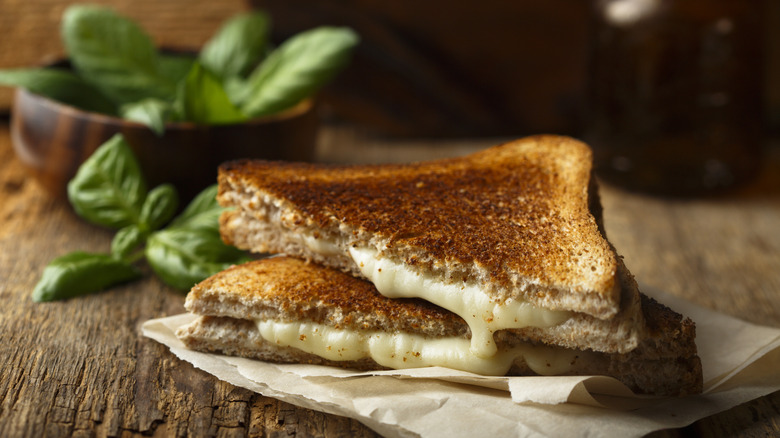 A grilled cheese sandwich with a bundle of fresh basil