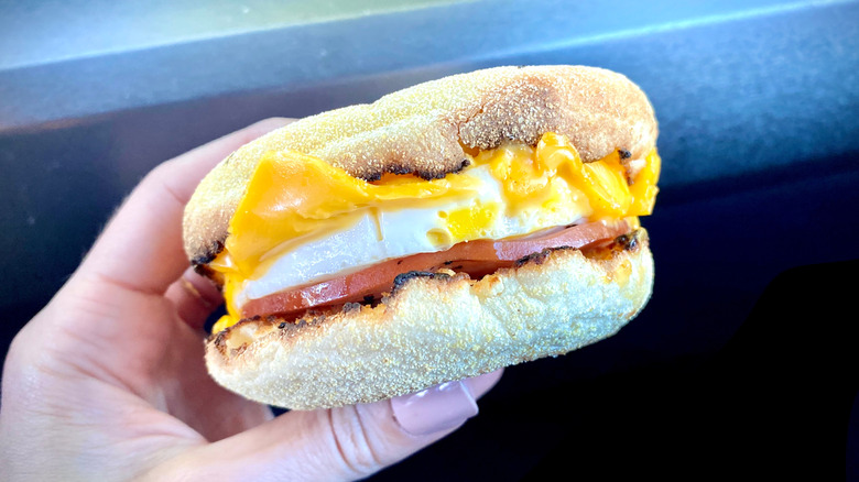 A hand holds a McDonald's Egg McMuffin.