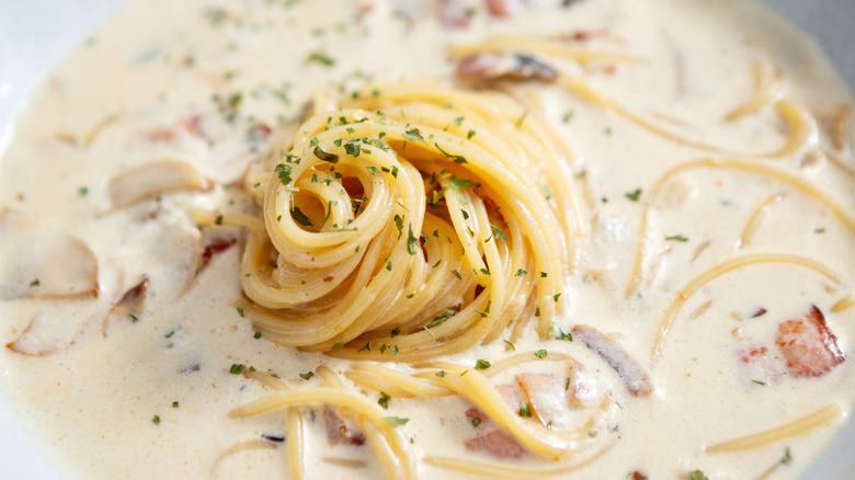 A bowl has pasta with clam chowder.