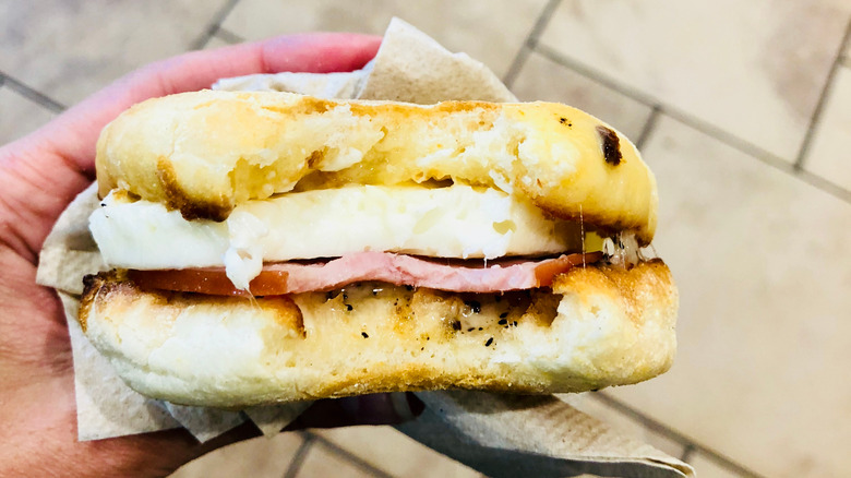 A hand holds a breakfast sandwich.