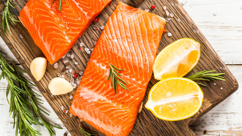 Raw salmon on a cutting board with aromatics