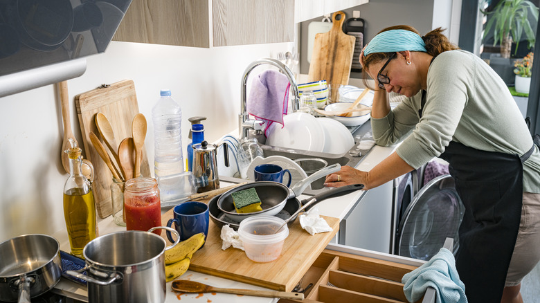 a homeowner looks stressed in a cluttered and messy kitchen