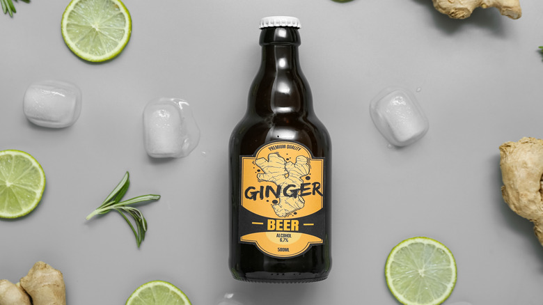 A bottle of ginger beer with ice, herbs, and limes