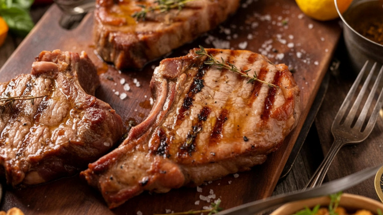 Grilled, bone-in pork chops on a wooden board.