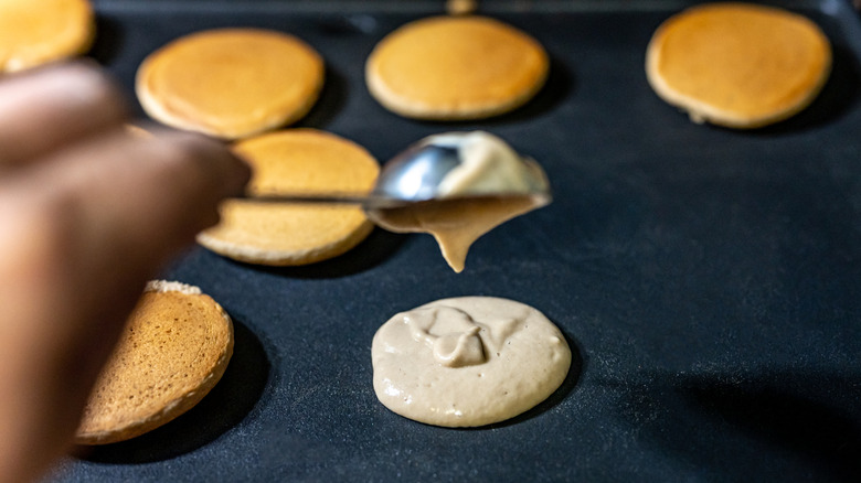 A home cook dispenses pancake batter onto a griddle to make silver dollar pancakes