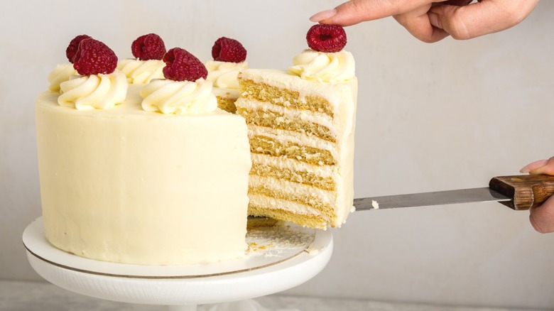 Yellow cake with white frosting topped with berries 