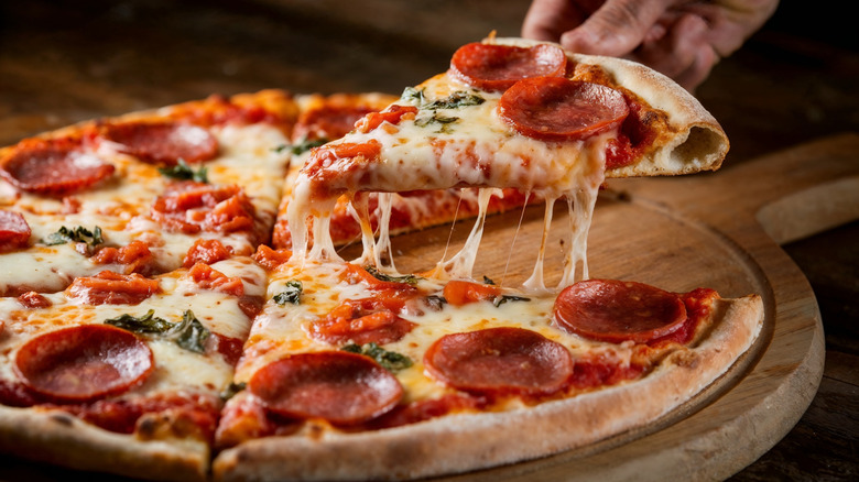 Pepperoni pizza as someone removes a slice