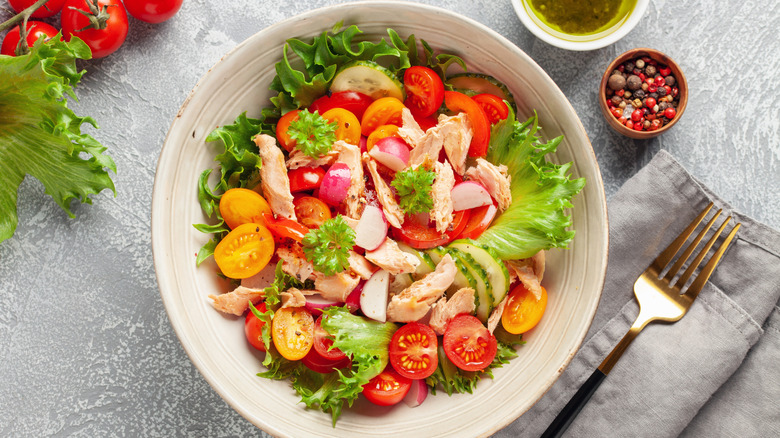 Salad with tomatoes, cucumber, and chicken in a white bowl