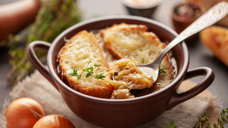 Someone dipping a spoon into French onion soup