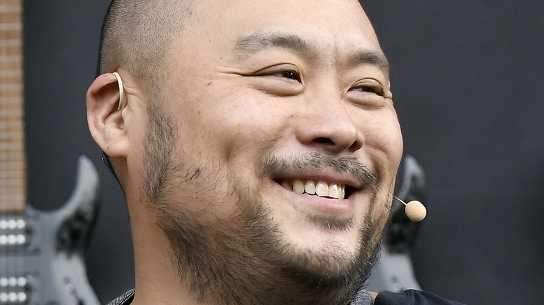 Smiling David Chang in front of guitars