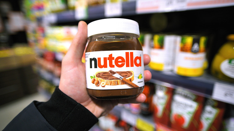 Close up of a person holding a jar of Nutella at a grocery store