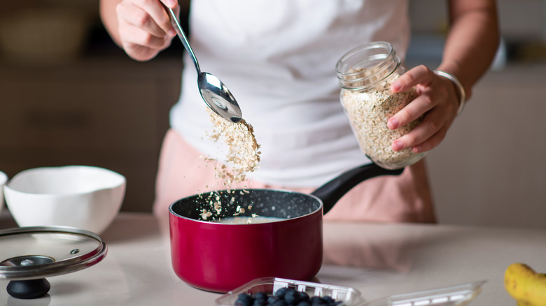 Cook spooning oats into pot