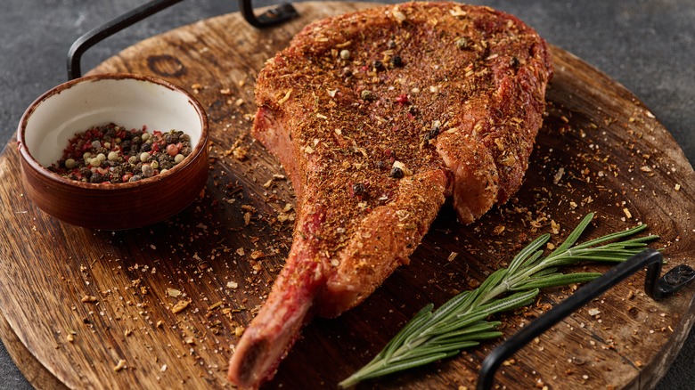 A dry-rubbed tomahawk steak on a wooden platter