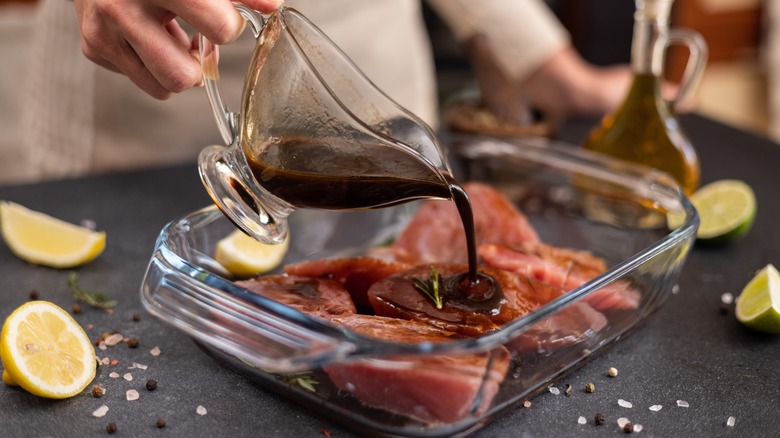 Chef pouring marinade over her meat before cooking