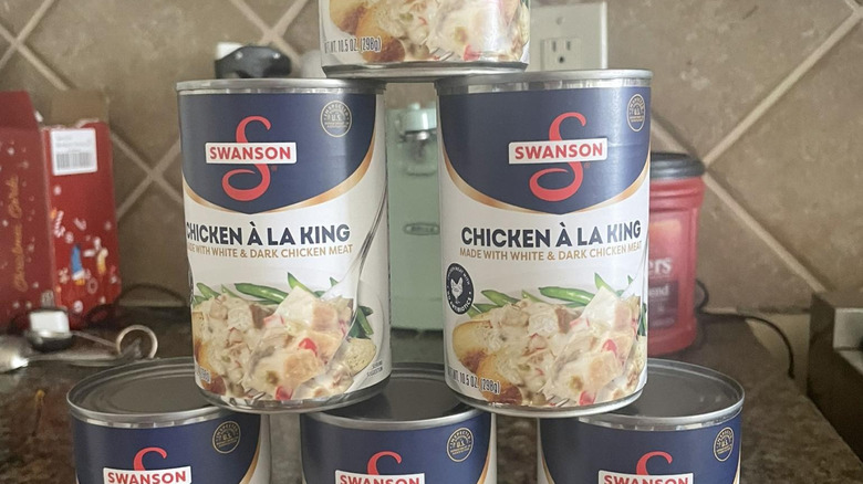 Cans of chicken a la king sit stacked in a pyramid shape.