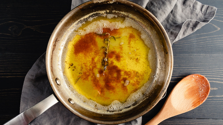 a stainless steel pan with browned butter and sprig of rosemary.