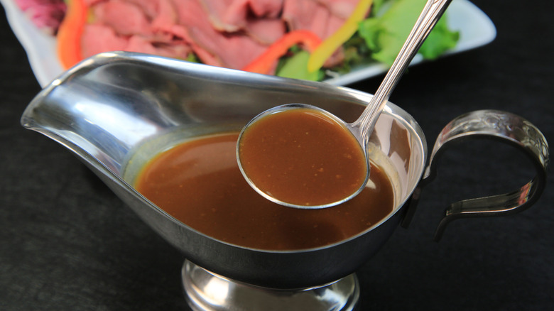 Au jus is ladled out of a gravy boat.
