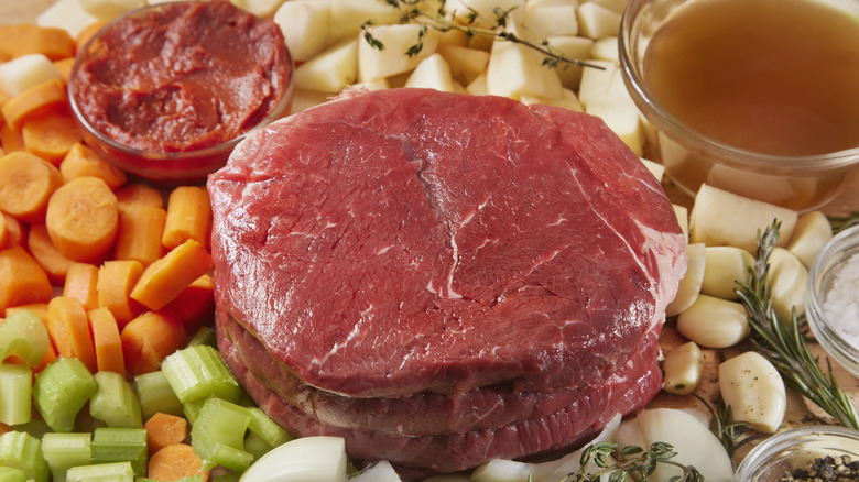 Raw ingredients for a pot roast sitting on a table