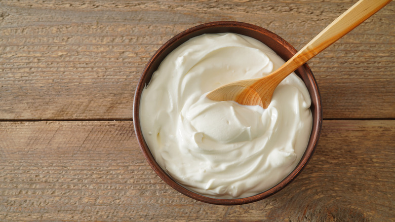 A wooden spoon sits in a bowl of crème fraîche