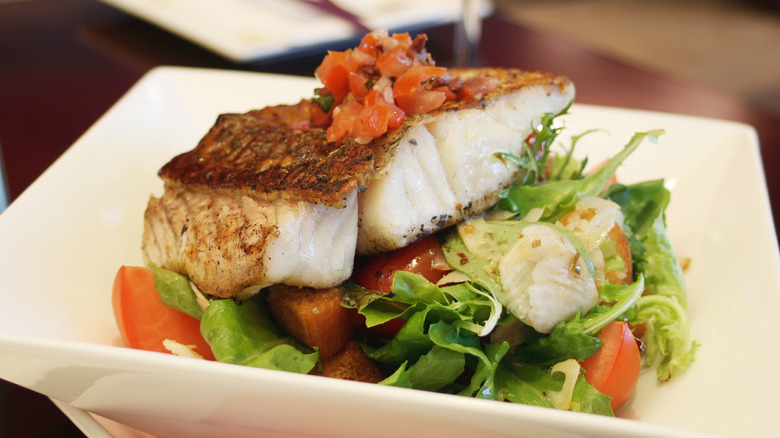 Barramundi served on a salad.