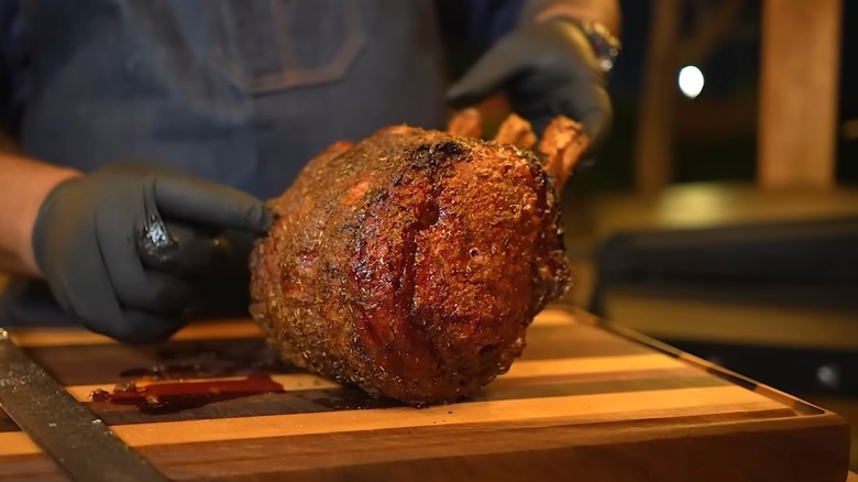 A smoked prime rib roast held up by gloved hands
